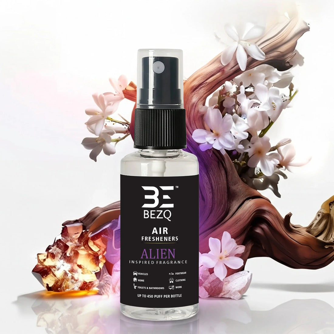Car air freshener spray bottle with black label, floral and wood accents in background.